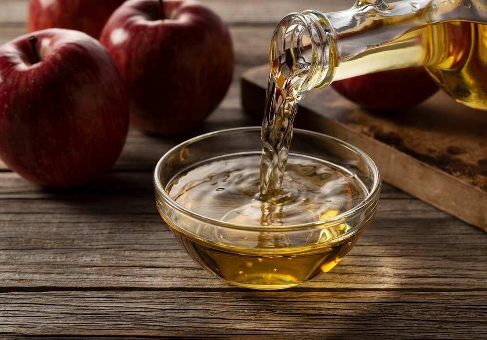 Is Vinegar Bad for Cats? Pouring apple cider vinegar into a glass container, showcasing its versatility for different applications